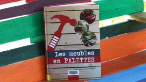 Livre "Les meubles en palettes" contre une palette peinte multicolore