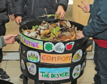 photo d'un vermicomposteur (décoré par les enfants) ouvert dans lequel un enfant met un déchet organique